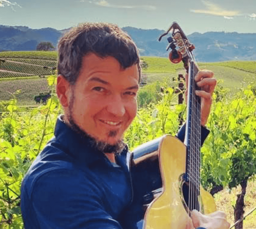 Daniel Fries with guitar in a vineyard